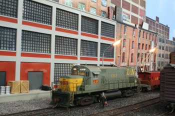 L&N C-420 idles in the yard with cab lights on and number boards lit, awaiting her next assignment. The engineer is on board checking things over while waiting for his conductor, with grip in hand who is about to board. 