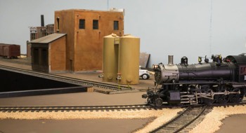 MoPac 4-8-0 #1817 rolls across the diamond; the Ste. Genevieve industrial area is in the background.